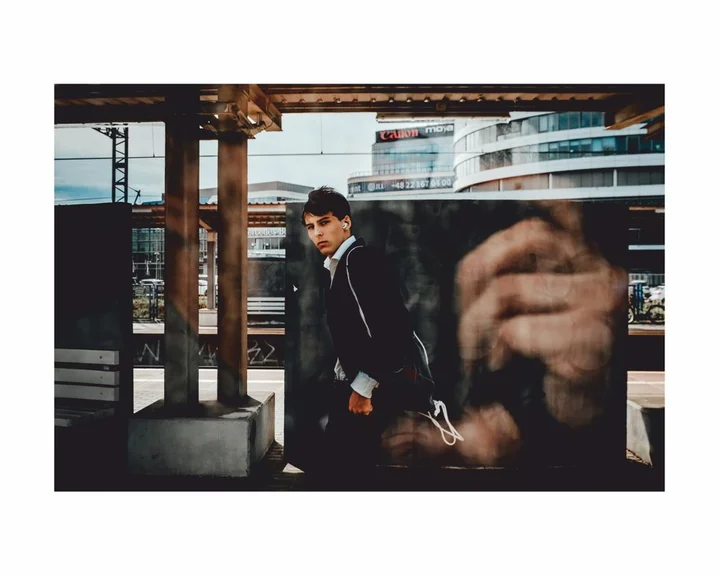 mezczyzna idacy kolo jezdni patrzacy na fotografa ktory odbija sie w szybie fotografujac